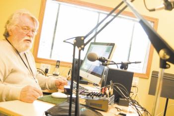 Bearded Ben James sits in headphones before a microphone in WEQY's production studio.